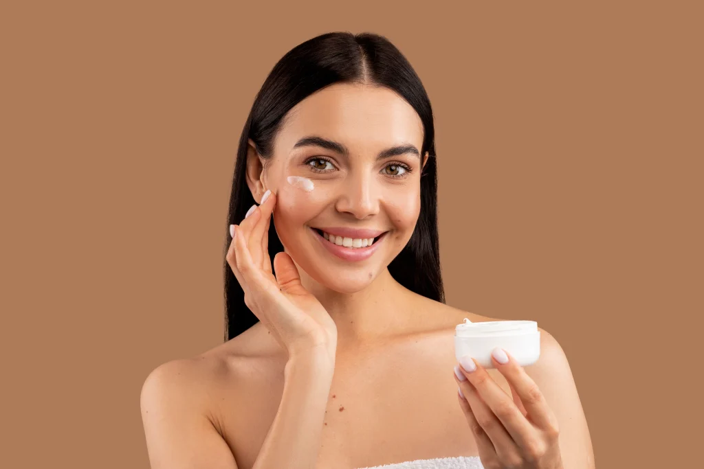 beautiful woman applying facial cream her skin